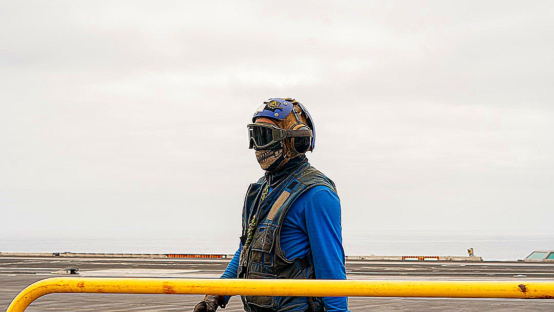 A sailor stands on a ship's deck.