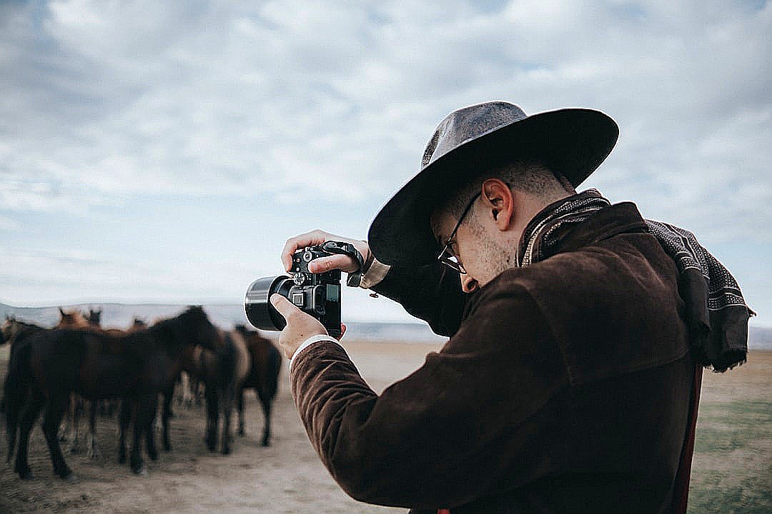 a man taking a picture of a herd of horses