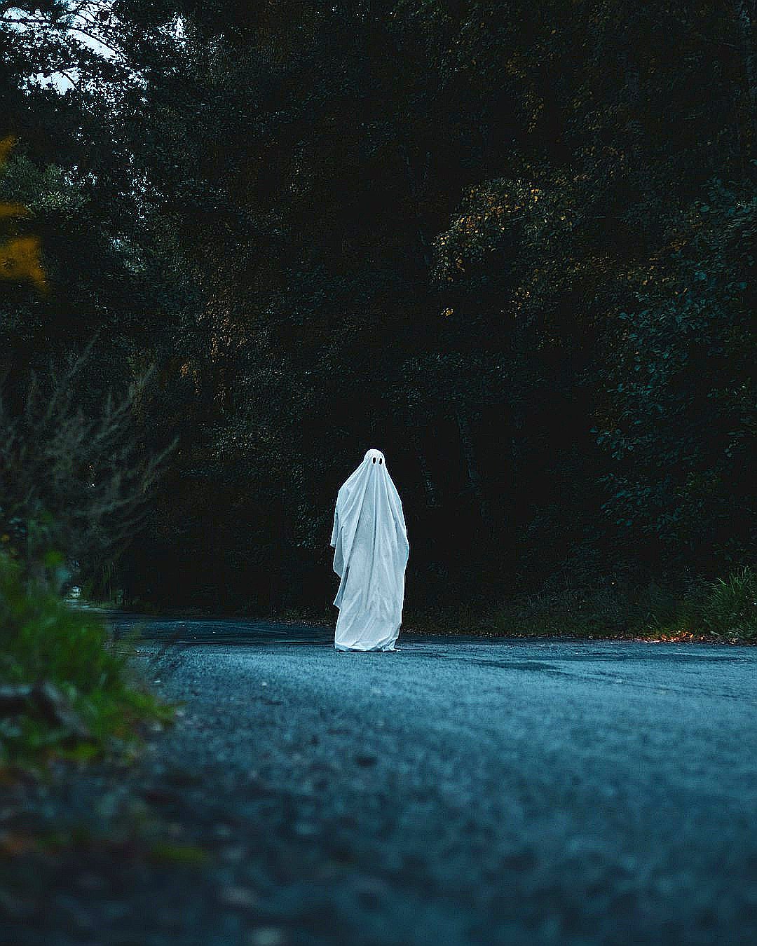 a ghost is walking down the road in the dark