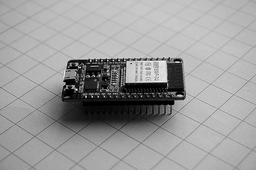 An ESP-32 microcontroller development board on a white grid paper surface